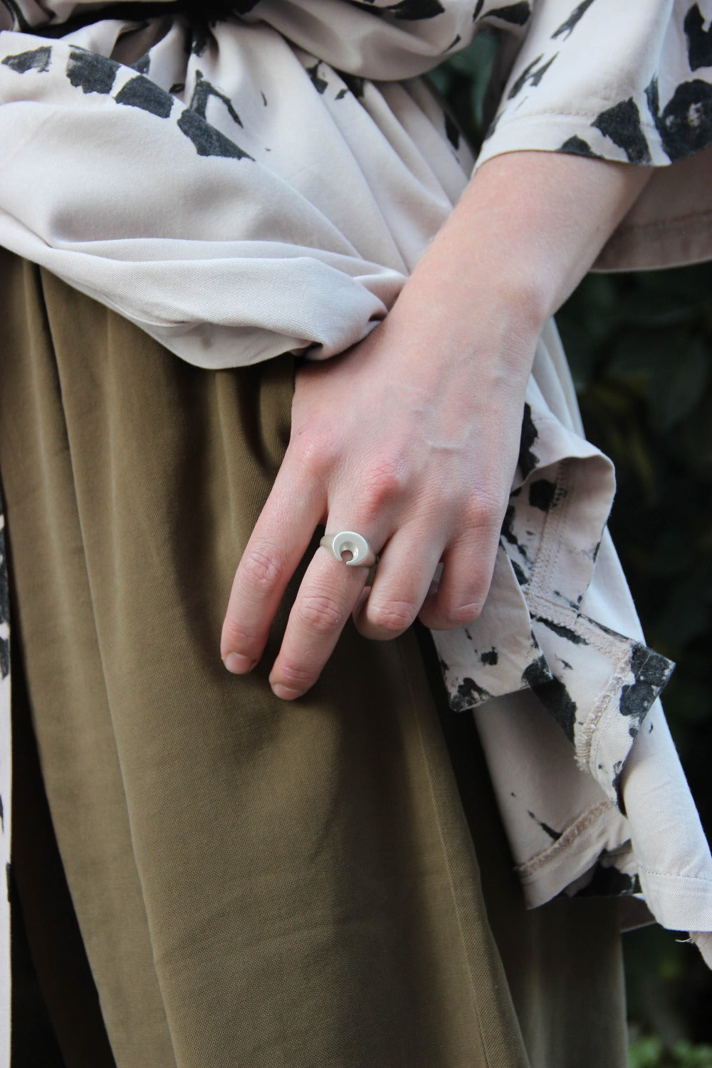 A silver ring featuring a brushed finish, handcrafted in the shape of a moon.