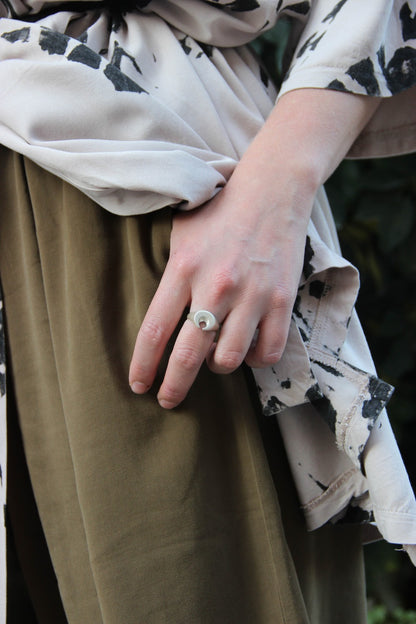 A silver ring featuring a brushed finish, handcrafted in the shape of a moon.