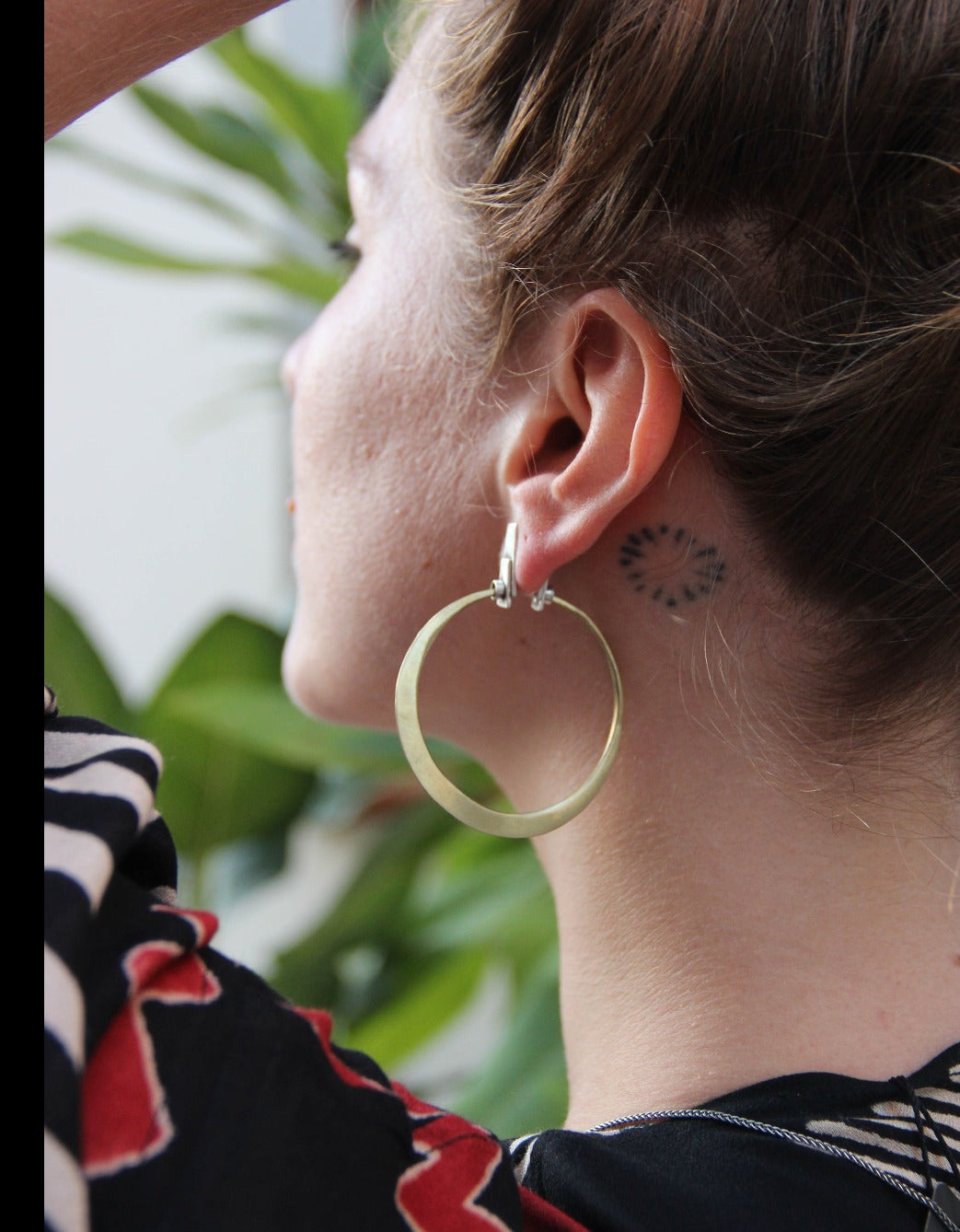 A pair of silver and brass hoop earrings with a brushed finish and a geometric design