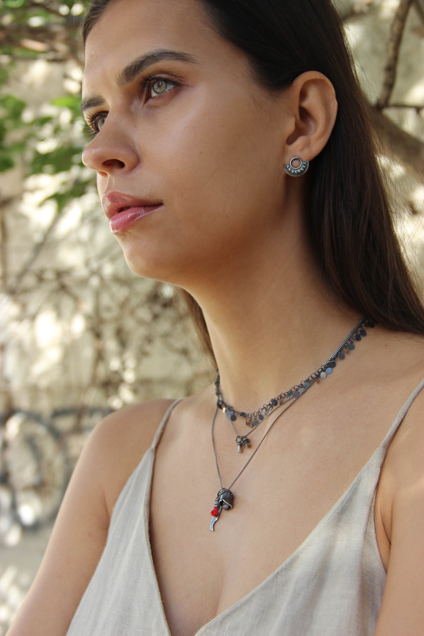 A pair of oxidized sterling silver dotted half moon earrings with a brushed finish