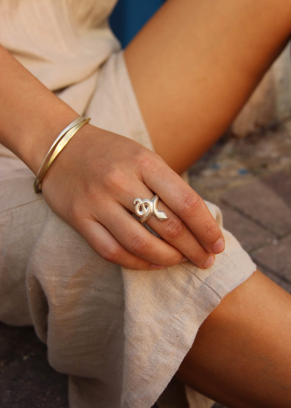 A silver ring featuring a brushed finish, handcrafted in the shape of a snake.