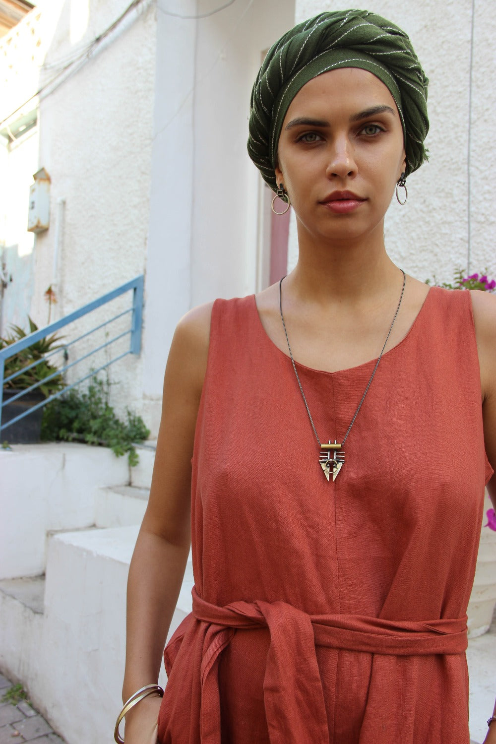 A silver and brass pendant necklace with a chain, featuring a warrior or praying mantis design.