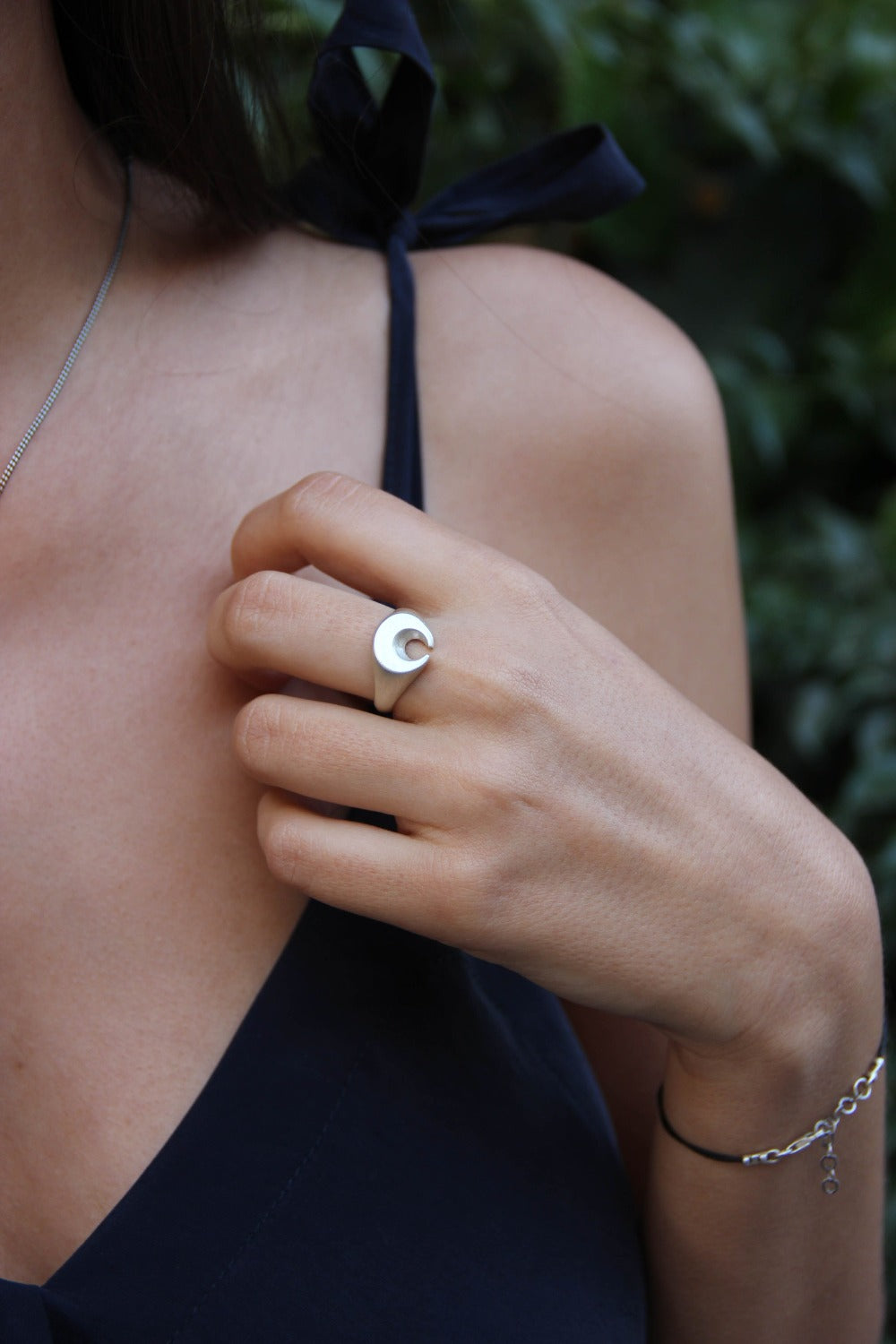 A silver ring featuring a brushed finish, handcrafted in the shape of a moon.