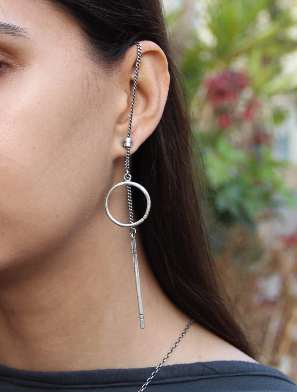 A pair of silver hoop earrings, one with a dangling tube design and the other with a chain hoop design, both made of sterling silver with a brushed finish.