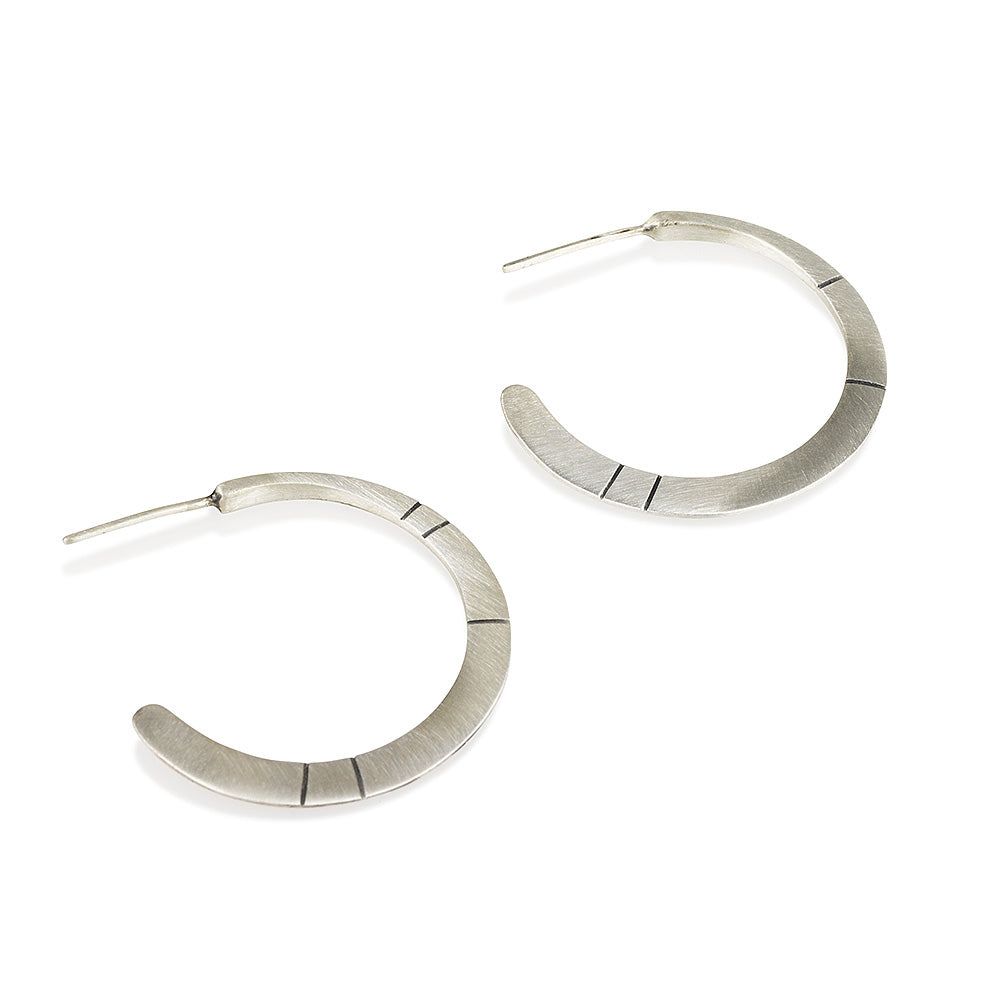 A pair of oxidized silver hoop earrings with a brushed finish, displayed against a white background.