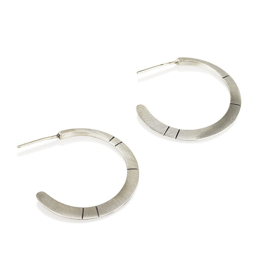 A pair of oxidized silver hoop earrings with a brushed finish, displayed against a white background.