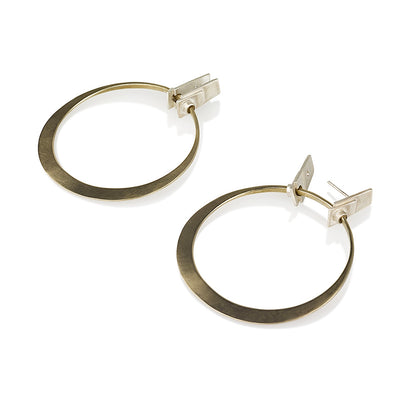 A pair of silver and brass hoop earrings with a brushed finish and a geometric design, displayed against a white background.