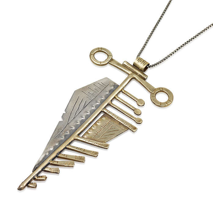 A sterling silver and brass necklace with a pendant featuring a design that resembles an arrow, attached to a chain.
