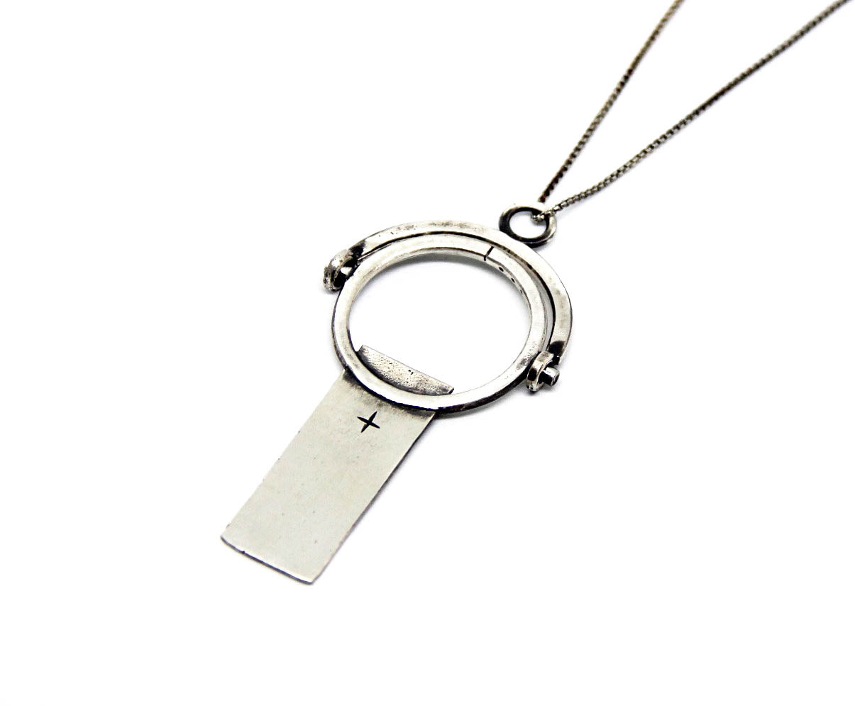 A sterling silver necklace with a magnifying glass pendant and a cross on the chain.