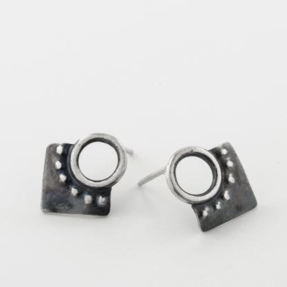 A pair of silver oxidized and brushed finish dotted rhombus earrings on a white background