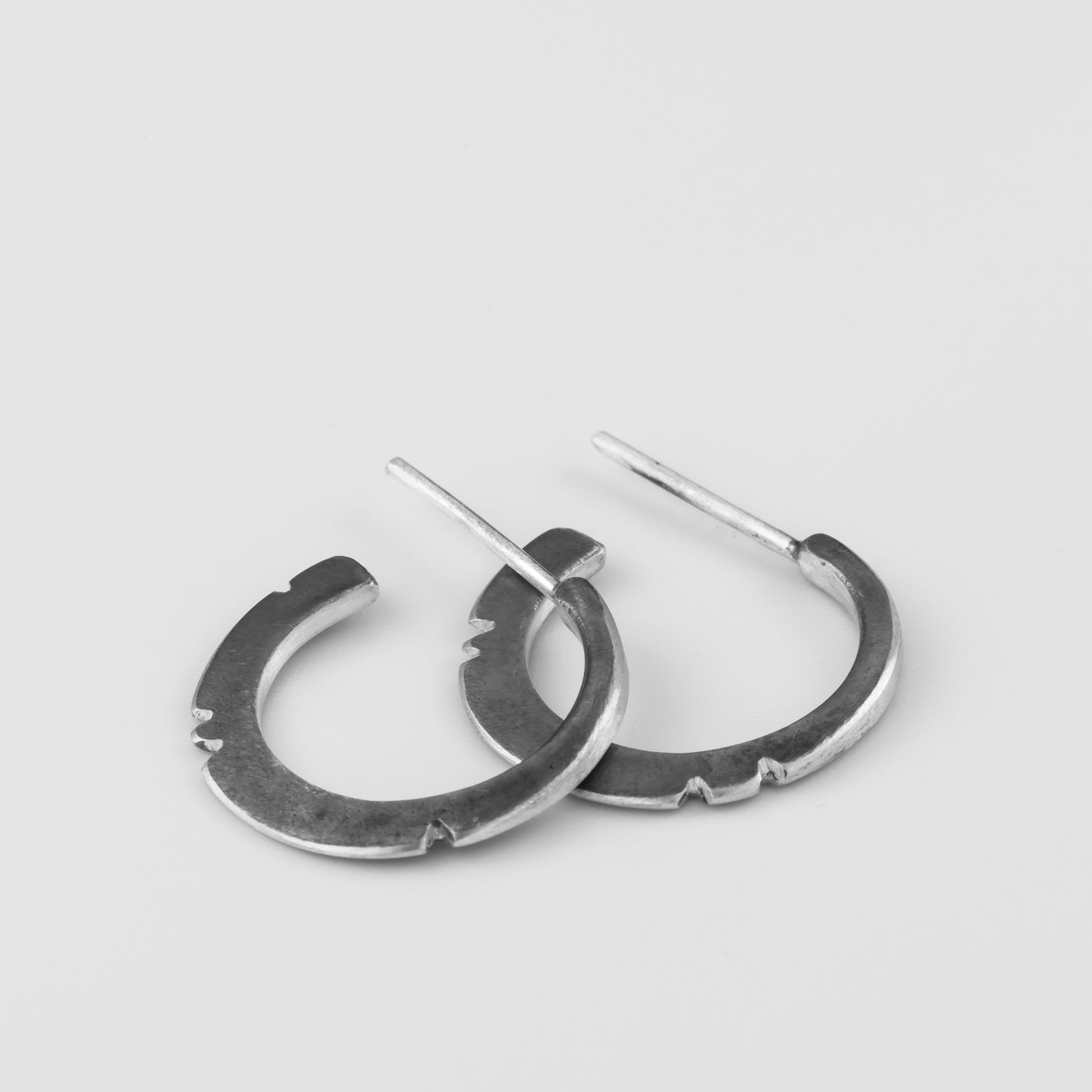 A pair of oxidized silver hoop earrings with a brushed finish, displayed against a white background.