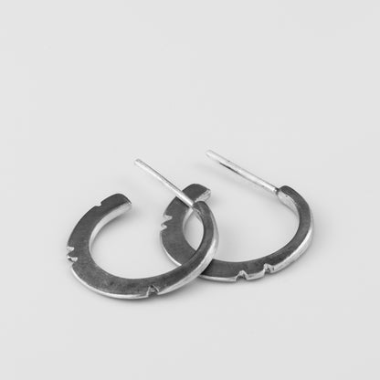 A pair of oxidized silver hoop earrings with a brushed finish, displayed against a white background.