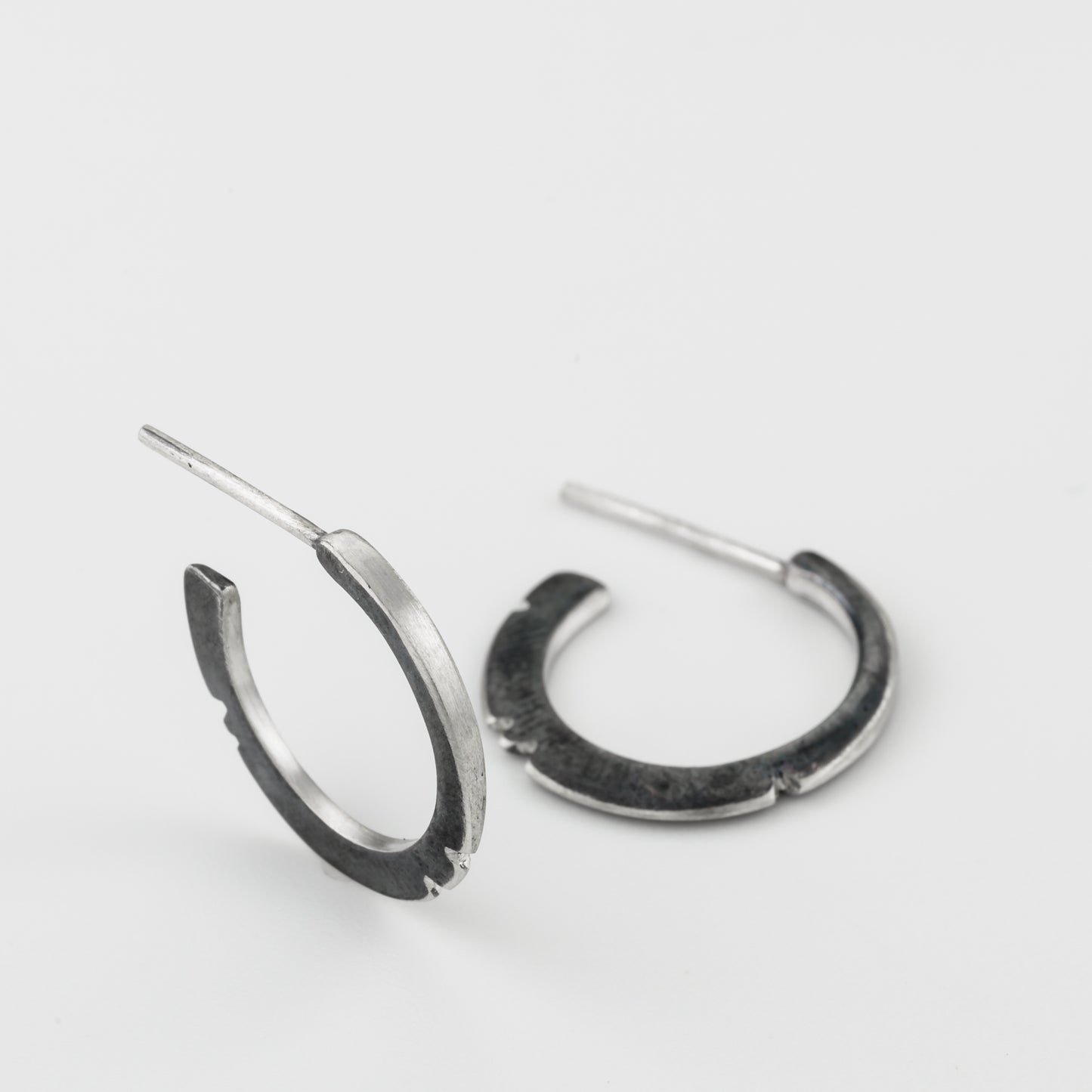 A pair of oxidized silver hoop earrings with a brushed finish, displayed against a white background.